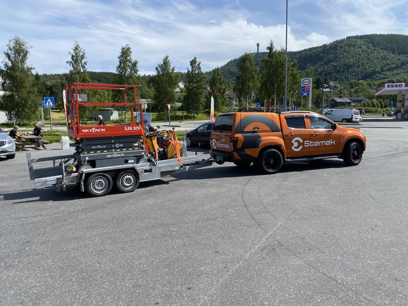 Stemek-pickup med utstyr på trailer i sommerlandskap